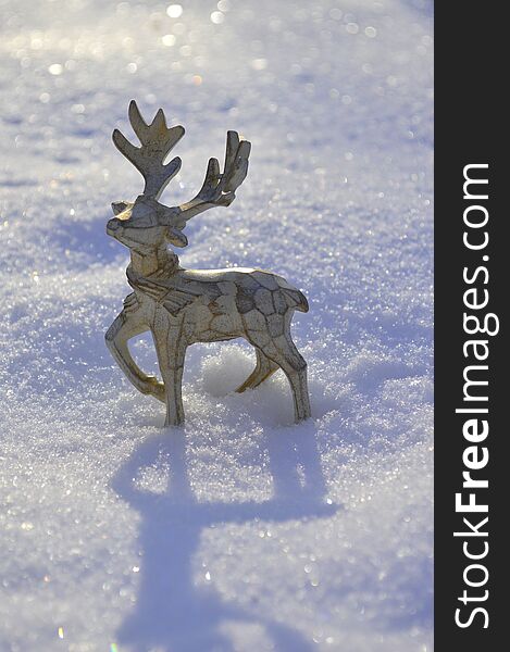 A beautiful wooden Christmas deer is standing in the snow. close up
