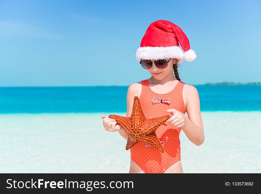 Little girl in Christmas hat on white beach during Xmas vacation. Little girl in Christmas hat on white beach during Xmas vacation
