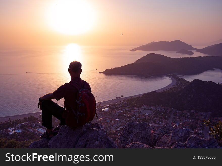 Traveler Relaxes On A Cliff And Admires The Amazing Sea Bay