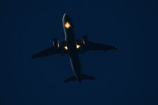 Airplane In The Sky At Sunset With Landing Lights On Stock Image