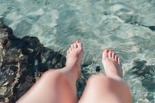 Woman`s Feet With Red Manicure Above Blue Sea Surface Stock Images