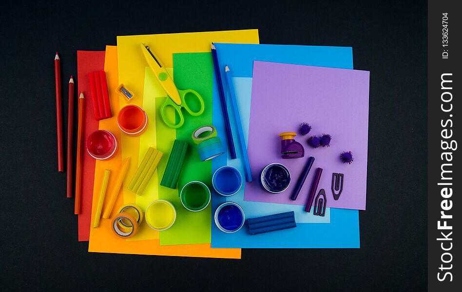 School accessories are laid out in the form of a rainbow. Black background.Happy back to school student. Art and crafts for kids. Child learning rainbow colors, alphabet letters and numbers