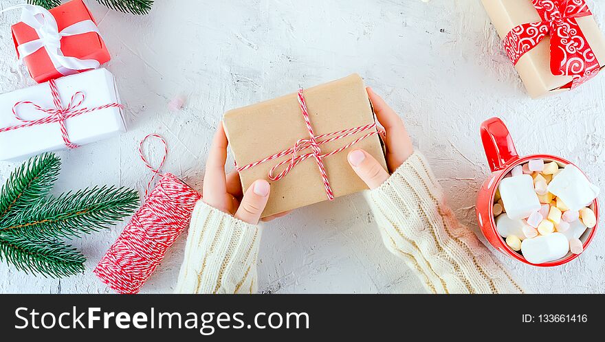 child is holding Christmas gift box tied with a red ribbon, red cup cocoa with marshmallow on the white background. Christmas card Holiday Concept, copy space. child is holding Christmas gift box tied with a red ribbon, red cup cocoa with marshmallow on the white background. Christmas card Holiday Concept, copy space