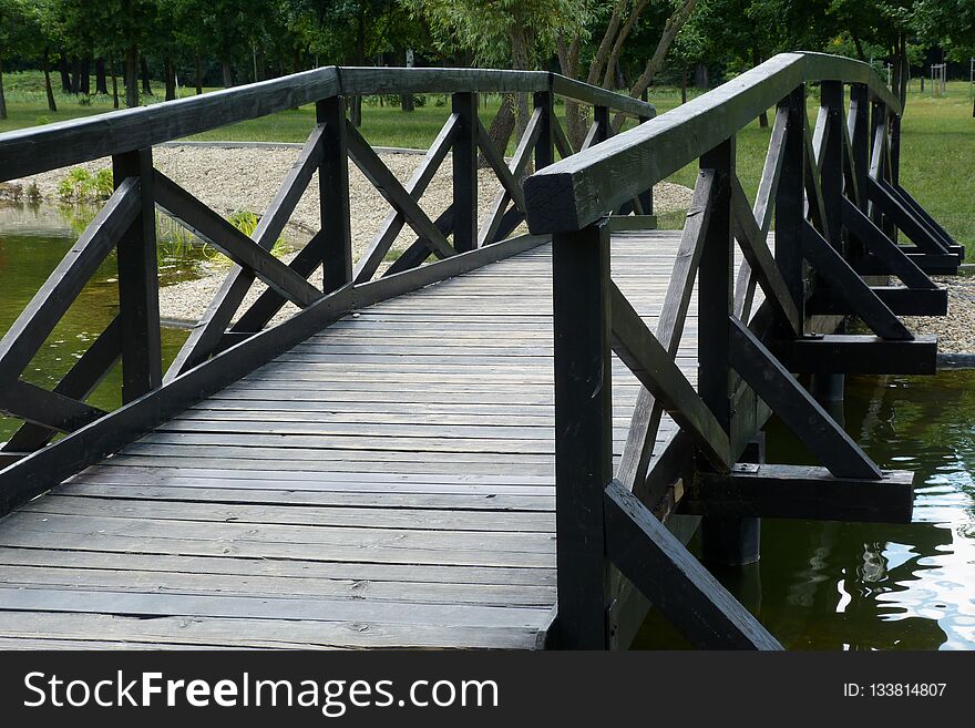 Wooden Foot Bridge Over Small Pond In Park