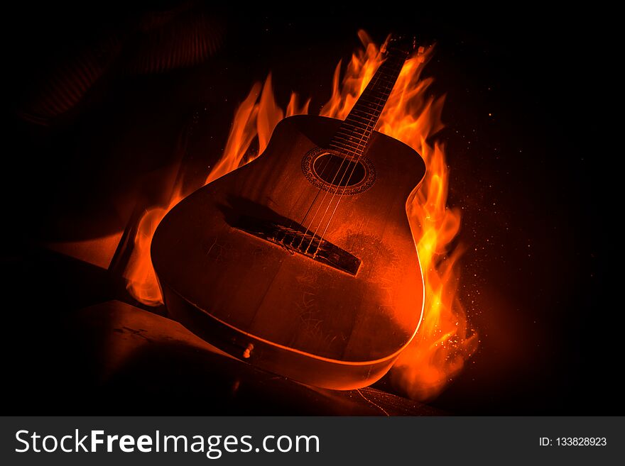Music concept. Acoustic guitar on a dark background under beam of light with smoke with copy space. Exploding guitar. Fire effects. Surreal guitar. Selective focus. Music concept. Acoustic guitar on a dark background under beam of light with smoke with copy space. Exploding guitar. Fire effects. Surreal guitar. Selective focus