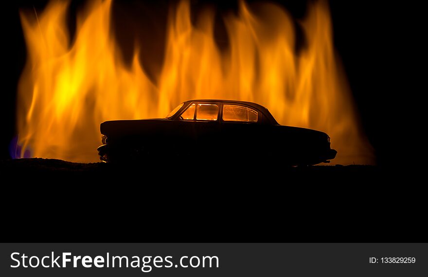Silhouette of old vintage car in dark foggy toned background with glowing lights in low light