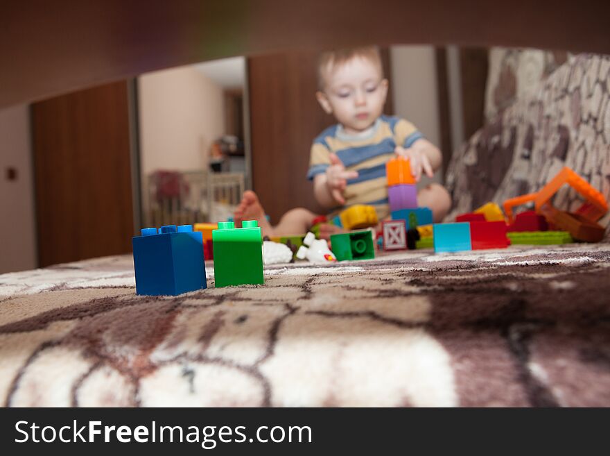 Sweet little boy building tower from cubes at home.