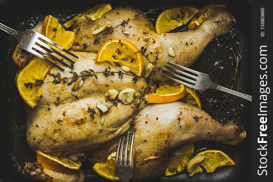 Christmas chicken on the pan with spices and orange slices. Selective focus. Shallow depth of field.