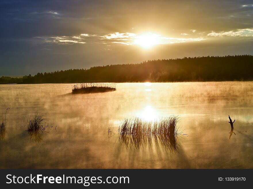 Landscape on a large lake with morning fog from the water, illuminated by the sun. Background.