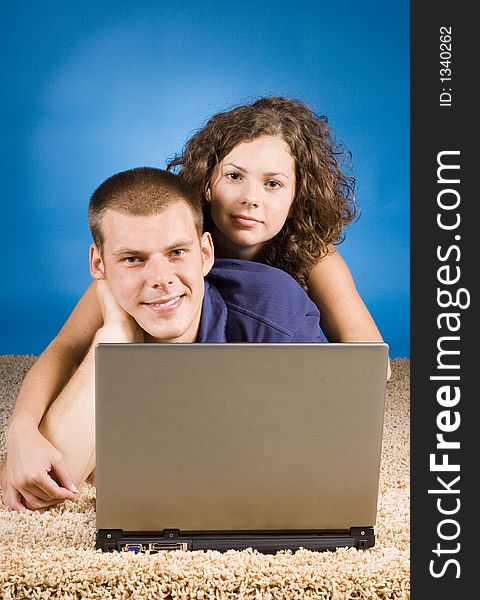 Young couple on the beige carpet with laptop. Young couple on the beige carpet with laptop