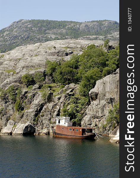 Picture of shipwreck in fjord near rocky coast.