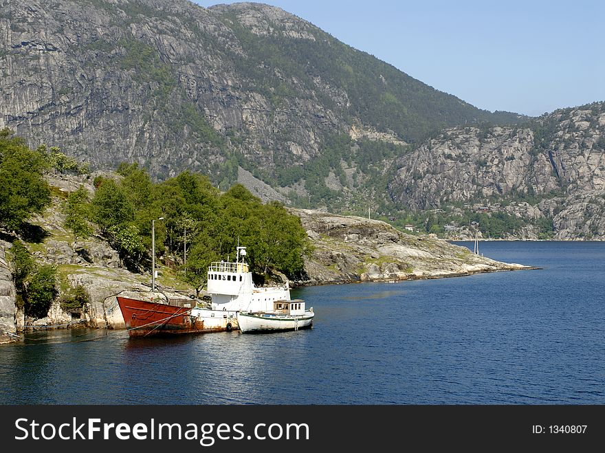 Picture of boat in fjord near rocky coast.