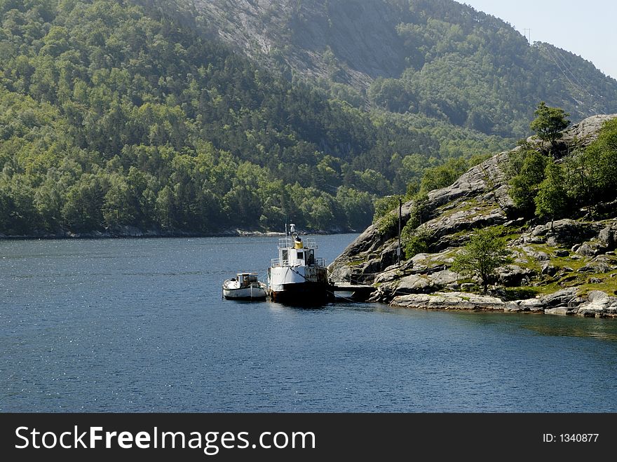 Picture of boat in fjord near rocky coast.