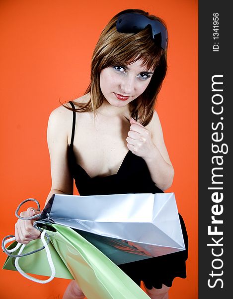 Brown haired young woman holds some shopping bags and a debit card - shopping addiction. Brown haired young woman holds some shopping bags and a debit card - shopping addiction