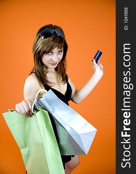 Brown haired young woman holds some shopping bags and a debit card - shopping addiction. Brown haired young woman holds some shopping bags and a debit card - shopping addiction