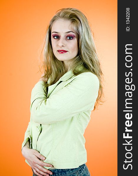 Portrait of a beautiful blond woman wearing  a casual jacket posing in a studio; nice make-up; isolated on orange background. Portrait of a beautiful blond woman wearing  a casual jacket posing in a studio; nice make-up; isolated on orange background