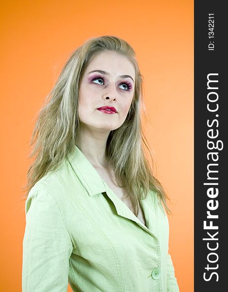 Portrait of a beautiful blond woman wearing a casual jacket posing in a studio; nice make-up; isolated on orange background. Portrait of a beautiful blond woman wearing a casual jacket posing in a studio; nice make-up; isolated on orange background