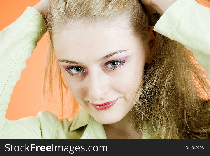 Portrait of a beautiful blond woman wearing  a casual jacket posing in a studio; nice make-up; isolated on orange background. Portrait of a beautiful blond woman wearing  a casual jacket posing in a studio; nice make-up; isolated on orange background