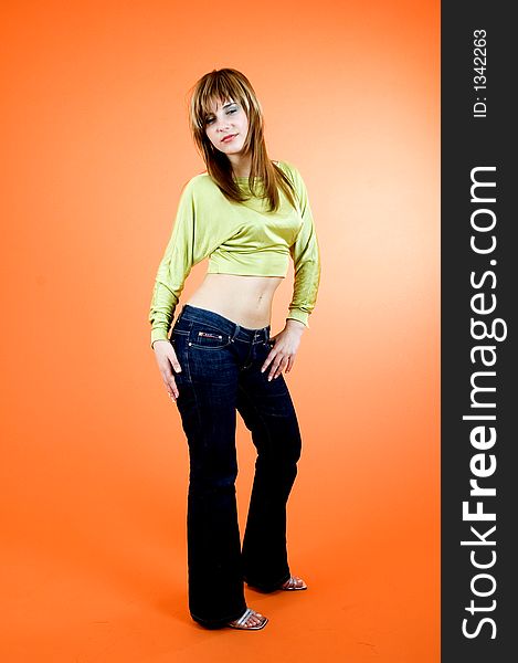 Beautiful young girl with nice looks and make-up posing in a studio; isolated on orange background; expression of youth. Beautiful young girl with nice looks and make-up posing in a studio; isolated on orange background; expression of youth