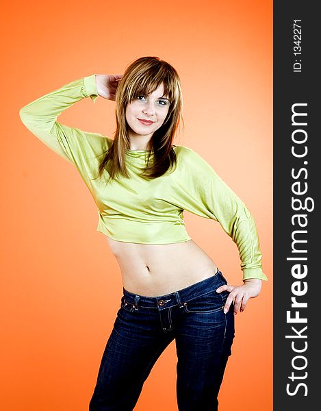 Beautiful young girl with nice looks and make-up posing in a studio; isolated on orange background; expression of youth. Beautiful young girl with nice looks and make-up posing in a studio; isolated on orange background; expression of youth