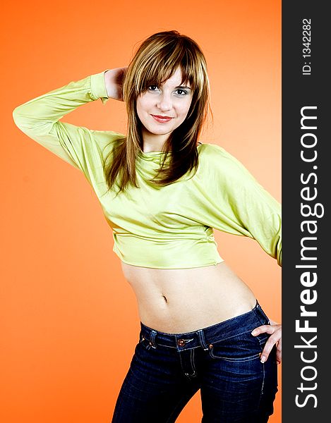 Beautiful young girl with nice looks and make-up posing in a studio; isolated on orange background; expression of youth. Beautiful young girl with nice looks and make-up posing in a studio; isolated on orange background; expression of youth