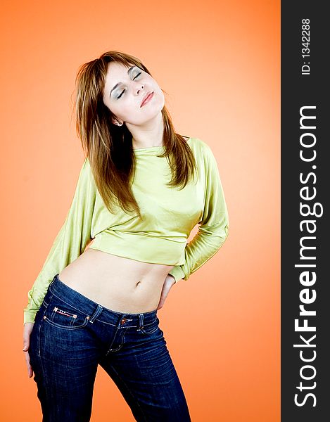 Beautiful young girl with nice looks and make-up posing in a studio; isolated on orange background; expression of youth. Beautiful young girl with nice looks and make-up posing in a studio; isolated on orange background; expression of youth