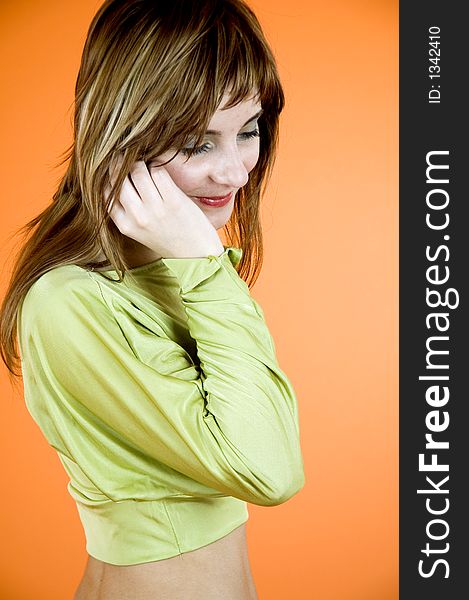 Young, attractive woman talking on her cellphone, over an orange background. Young, attractive woman talking on her cellphone, over an orange background