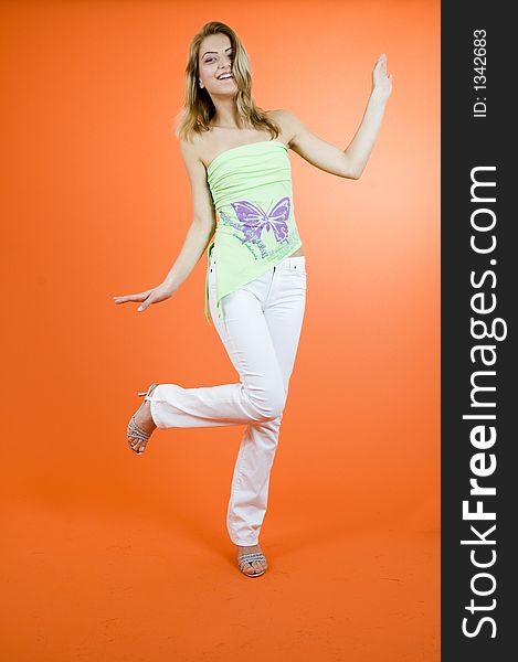 Beautiful blond girl dancing; casual clothes; orange background. Beautiful blond girl dancing; casual clothes; orange background