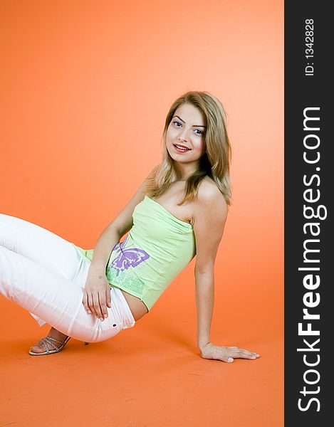 Portrait of a beautiful blond girl posing in a studio, smiling and lookind confident in her youth; orange background. Portrait of a beautiful blond girl posing in a studio, smiling and lookind confident in her youth; orange background