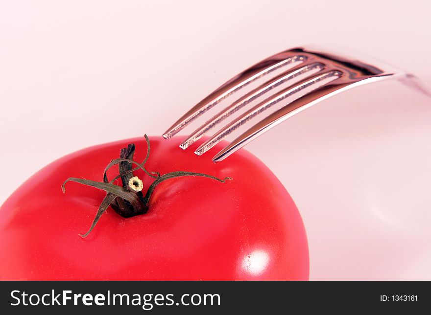 Tomato and fork closeup, white background