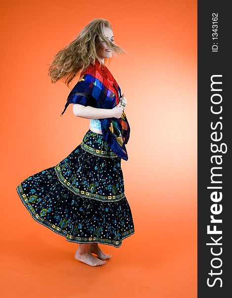 Pretty model with curly blond hair dances a gypsy dance over an orange background. Pretty model with curly blond hair dances a gypsy dance over an orange background.