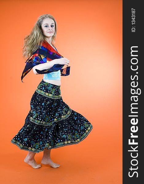 Pretty model with curly blond hair dances a gypsy dance over an orange background. Pretty model with curly blond hair dances a gypsy dance over an orange background.