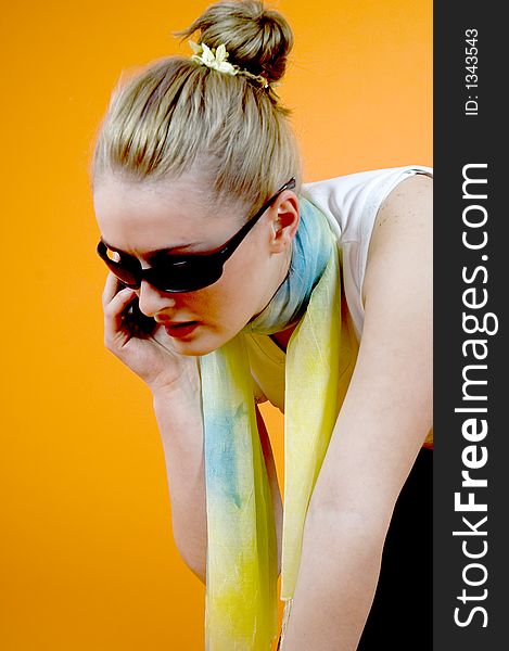 Portrait of a beautiful young blond with casual clothes speaking on the cellular; nice looks and make-up; isolated on orange. Portrait of a beautiful young blond with casual clothes speaking on the cellular; nice looks and make-up; isolated on orange
