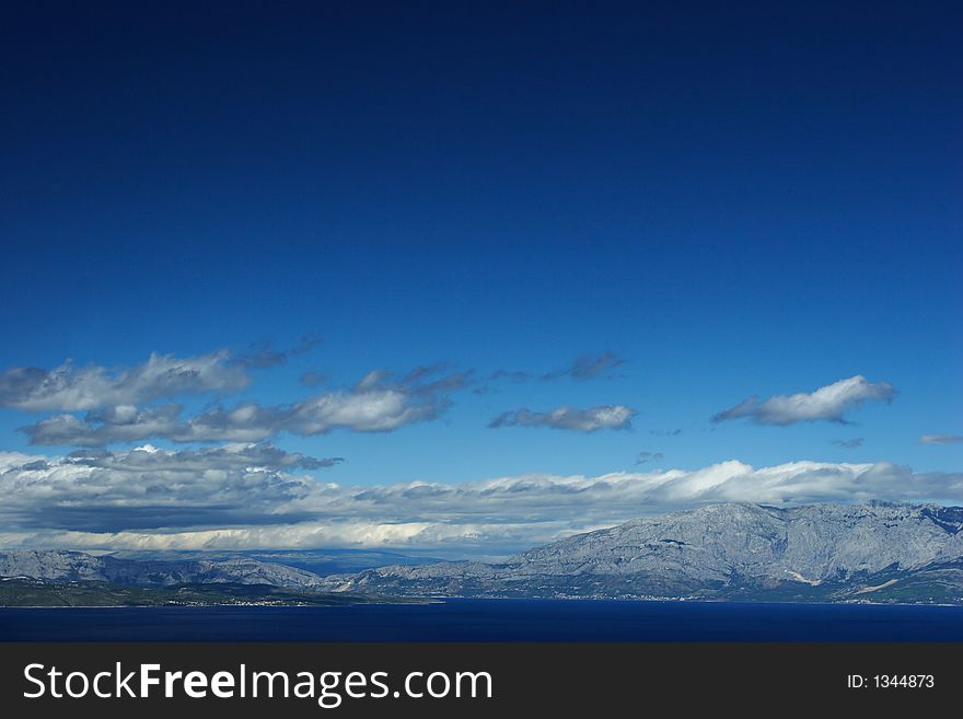 Mediterranean landscape on a summer day, clouds over sea and mountains
