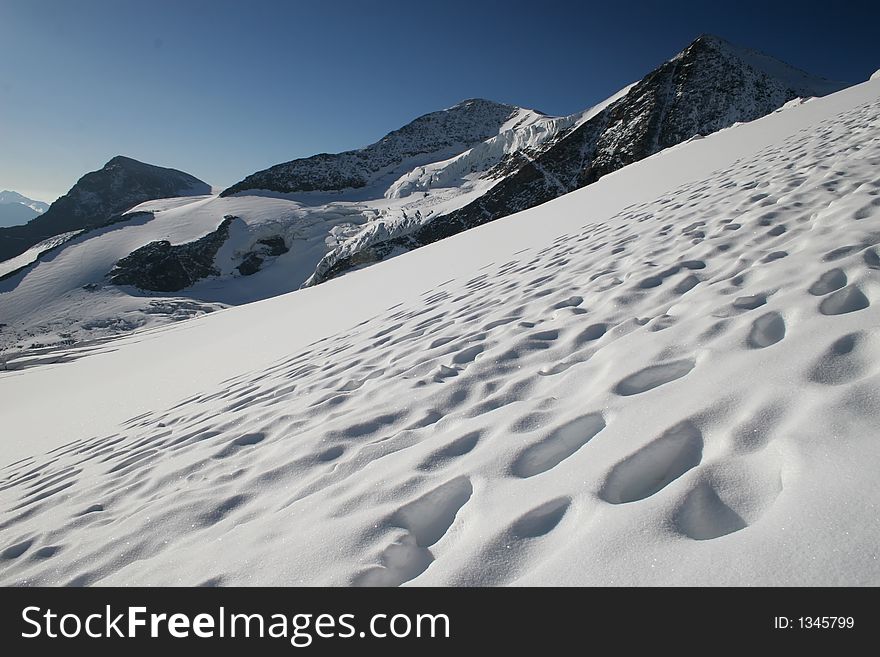 Path on a glacier. Bootprints in the snow