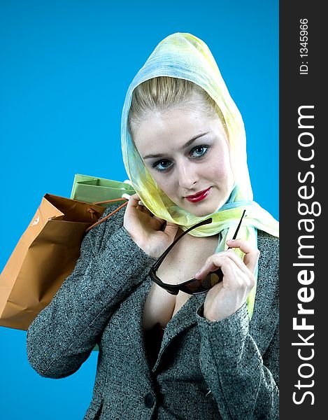 Portrait of a beautiful young blond with casual clothes and holding two shopping bags on her shoulder; nice looks and make-up; isolated on blue. Portrait of a beautiful young blond with casual clothes and holding two shopping bags on her shoulder; nice looks and make-up; isolated on blue