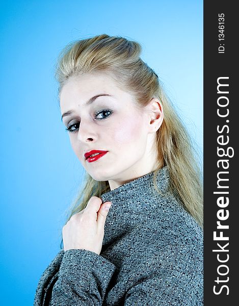 Portrait of a good-looking woman with sensual red lips and beautiful eyes; posing in a studio; isolated on blue background. Portrait of a good-looking woman with sensual red lips and beautiful eyes; posing in a studio; isolated on blue background