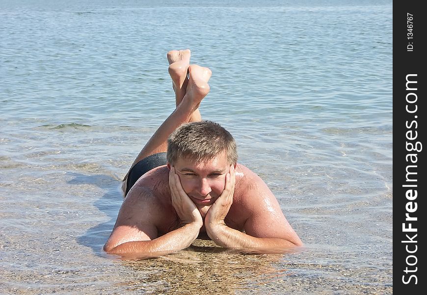 Young man posing laying in shallow sea water. Young man posing laying in shallow sea water