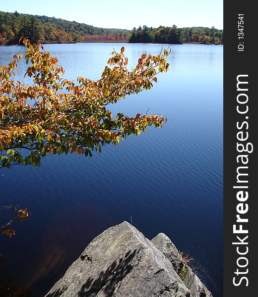 Triangle shape stone ashore. Small lake in foliage time