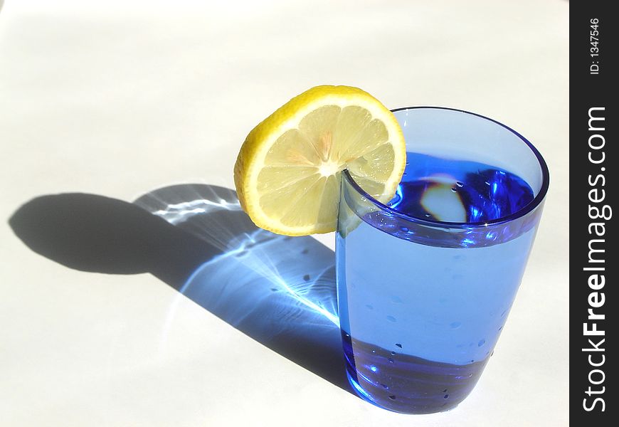 Cocktail drink decorated with lemon and served in a blue glass. Cocktail drink decorated with lemon and served in a blue glass
