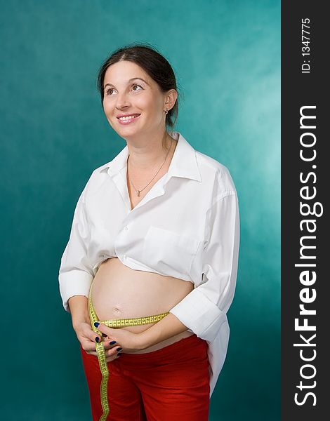 A pregnant woman measuring her growing belly. A pregnant woman measuring her growing belly