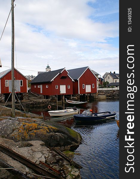 Old fischerman's cottages at the harbour of fishing village Bud. Rocks and little boats at the foreground. Old fischerman's cottages at the harbour of fishing village Bud. Rocks and little boats at the foreground.