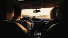 A Married Couple Travels By Car, The Setting Sun Illuminates Them. Asian Man Driving Stock Image