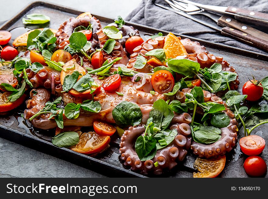 Whole octopus salad with orange, tomatoes and cress salad served on board with wine.