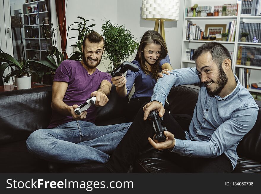 Happy excited friends playing video games at home together and having fun. Concept about technology, people and lifestyle