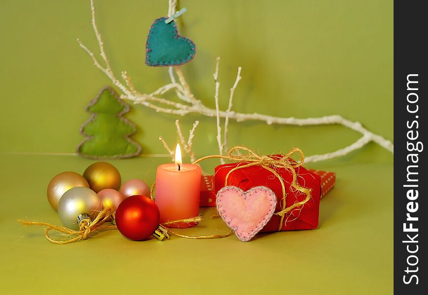 Decorative seasonal composition of a burning candle, felt hearts, Christmas-tree balls, Christmas decor, romantic interior