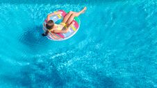 Aerial Drone View Of Little Girl In Swimming Pool From Above, Kid Swims On Inflatable Ring Donut , Child Has Fun In Blue Water Stock Photography