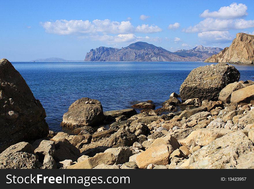 Seascape - stone, clear water, and in the distance an old volcano. Seascape - stone, clear water, and in the distance an old volcano