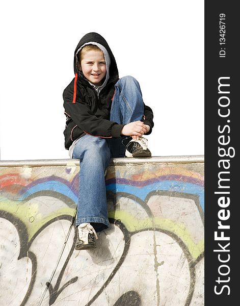 A vertical image of a teenage male sitting on a graffeti covered wall with the background whit ready for copy. A vertical image of a teenage male sitting on a graffeti covered wall with the background whit ready for copy