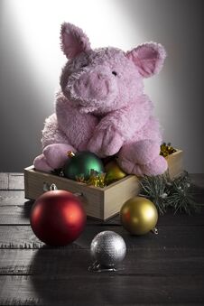Toy Pig Sitting On Box With New Year Balls On Wooden Surface. Festive Card, Chinese New Year Of Pig, Zodiac Symbol 2019 Stock Photo